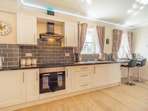 a kitchen with white cabinets and a clock on the wall at Squirrel Cottage - Uk37886 in Stanhope
