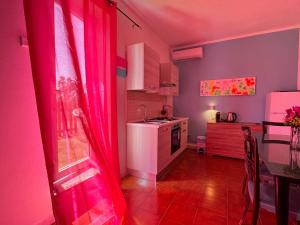 a kitchen with a pink curtains and a table and a kitchen at La Nuova Rinascita in San Giovanni Suergiu