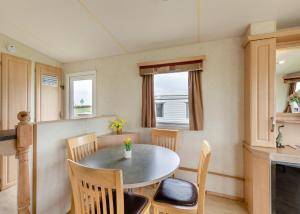 a kitchen and dining room with a table and chairs at Rowanbank Caravan Park in Beckfoot
