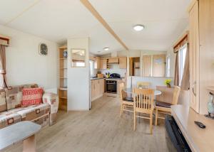 a kitchen and living room with a table and chairs at Rowanbank Caravan Park in Beckfoot +24 photos