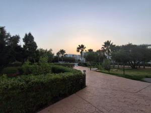 a brick walkway in a park with trees and bushes at Appartement Residence Tafoult IMIOUADDAR in Agadir nʼ Aït Sa