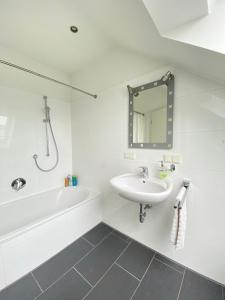 a bathroom with a sink and a tub and a mirror at Midi-Maisonette mit kleiner Dachterrasse und Blick ins Grüne in Petersberg +4 photos