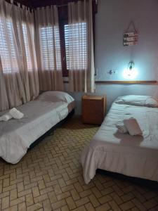 two beds sitting in a room with windows at Hotel Praise in Capilla del Monte