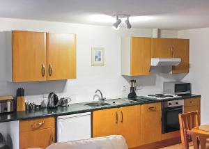 a kitchen with wooden cabinets and a sink at Avalon Cottages in Llangynin