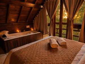 a bedroom with a tub and a bed with two towels at Cabanas dos Plátanos in Gramado +122 photos