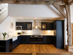 a kitchen with black cabinets and black appliances at Hatchers Barn - Uk42080 in East Garston +21 photos