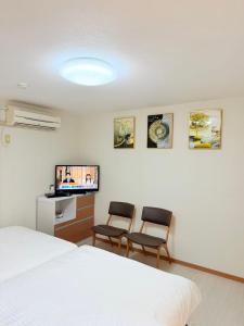 ein Hotelzimmer mit zwei Stühlen und einem Fernseher in der Unterkunft MUTSUMI Hotel in Saga