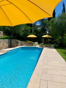 a swimming pool with a yellow umbrella and two umbrellas at LA PERASCEDA in Spéracèdes