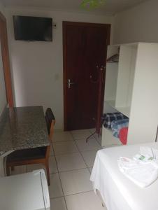 a room with a bed and a table and a door at Hotel Maciel in Ponta Grossa +5 photos