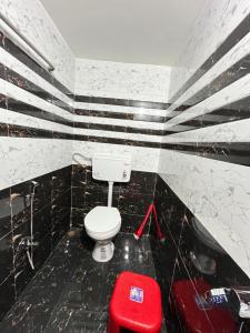 a bathroom with a white toilet and a red stool at Satvik Homestay in Devgarh
