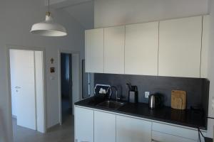 a kitchen with white cabinets and a black counter top at Apartman Mala Artica in Drage