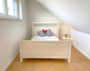 a bedroom with a white bed with a red heart pillow at Midi-Maisonette mit kleiner Dachterrasse und Blick ins Grüne in Petersberg