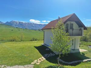 a small house in a field with mountains in the background at Horizont Cemerno in Podborina