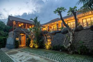 a house with a stone wall and palm trees at Soulstar Villa Ubud in Ubud