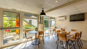 a dining room with tables and chairs and windows at Premiere Classe Versailles - Saint Cyr L'ecole in Saint-Cyr-lʼÉcole