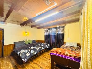 a bedroom with two beds in a room at Negi Wooden House in Manāli