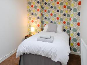 a bedroom with a white bed with a patterned wall at Drumwherry By The Sea in Monreith