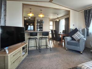 a living room with a flat screen tv and a kitchen at Millars Caravan in Ayr