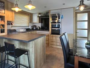 a kitchen with a large island with black chairs at Millars Caravan in Ayr
