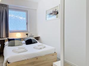 a bedroom with a bed with white sheets and a window at Apartment Titti - GLA133 by Interhome in Gera Lario