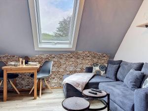 a living room with a blue couch and a brick wall at Apartment Eifelhome One nahe Nürburgring by Interhome in Fuchshofen