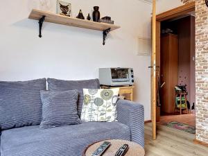 a living room with a blue couch and a microwave at Apartment Eifelhome One nahe Nürburgring by Interhome in Fuchshofen