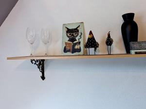 a shelf with wine glasses and a picture of a cat at Apartment Eifelhome One nahe Nürburgring by Interhome in Fuchshofen +24 photos