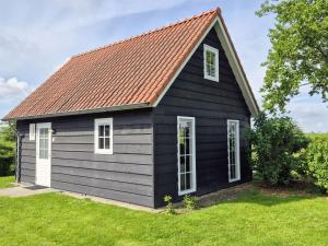 a black house with a red roof at Holiday Home Zeeuwse Cottage Wemeldinge-1 by Interhome in Wemeldinge