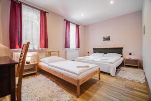 two beds in a room with red curtains at Panoráma Vendégház Bükkösd in Bükkösd