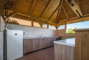 a kitchen with a white refrigerator and wooden cabinets at Panoráma Vendégház Bükkösd in Bükkösd