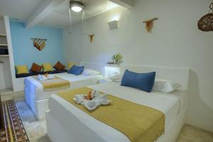 two beds in a room with blue and white at Kin Ha Tulum Hotel in Tulum