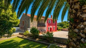 a red house with a palm tree in front of it at La Venta de Pedro in Ribadesella
