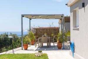 a patio with a table and chairs under a pergola at Villa Eftychia - Panoramic Sea View in Svoronata