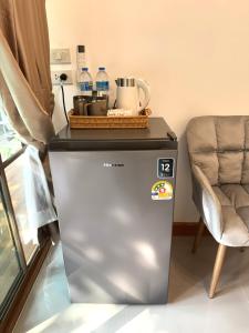 a small refrigerator in a room with a chair at ลิตเติ้ล แคมป์ ชะอม in Ban Bung Mai