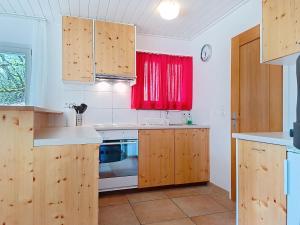 a kitchen with wooden cabinets and a red window at Apartment Chalet Holzwurm-1 by Interhome in Grindelwald