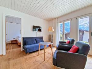 a living room with two blue couches and a table at Apartment Chalet Holzwurm-1 by Interhome in Grindelwald