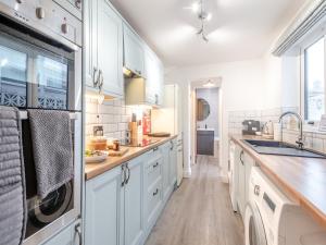 a kitchen with white cabinets and a sink at Big Skies in Lowestoft