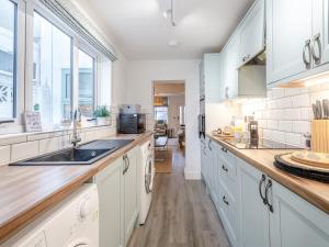 a kitchen with white cabinets and a sink at Big Skies in Lowestoft