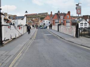an empty street with people walking across a bridge at Bosuns Rest - 16265 in Staithes