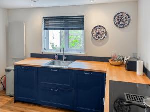 a blue kitchen with a sink and a window at Tigh An Dun in Luib