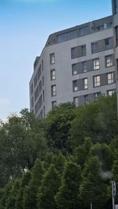 a tall building with trees in front of it at Vijolie West Exclusive in Warsaw