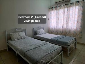 two twin beds in a room with a window at Osvy Palm Homestay in Penampang +3 photos