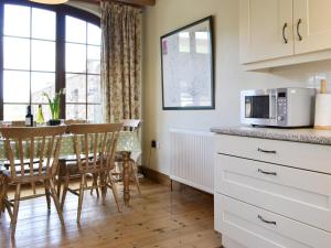 a kitchen with a table with chairs and a microwave at Cass Lodge in Huby