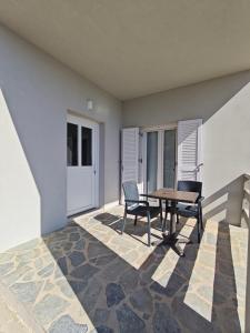 a patio with a table and chairs in a room at Tramonto Nel Delfini in Kini