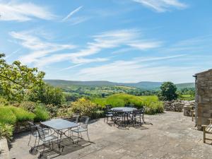 a patio with tables and chairs and a view of the hills at Town Head Cottage in Carlton
