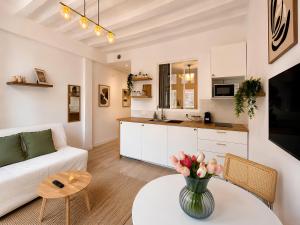 a living room with a couch and a table with a vase of flowers at Saint Maclou Plein Centre Rouen Malpalu - Linge & Ménage Inclus in Rouen