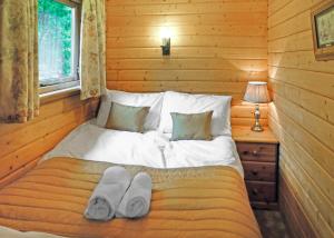 a bed in a log cabin with towels on it at Goodiford Mill Lakes in Kentisbeare +17 photos