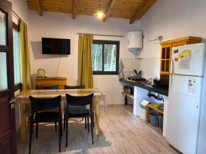 a kitchen with a table and chairs and a refrigerator at Cabañas Nido Escondido in Villa Ciudad Parque