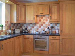 a kitchen with wooden cabinets and a stove top oven at Goslings in Marloes