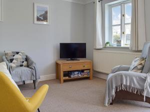 a living room with a tv and two chairs at Goslings in Marloes